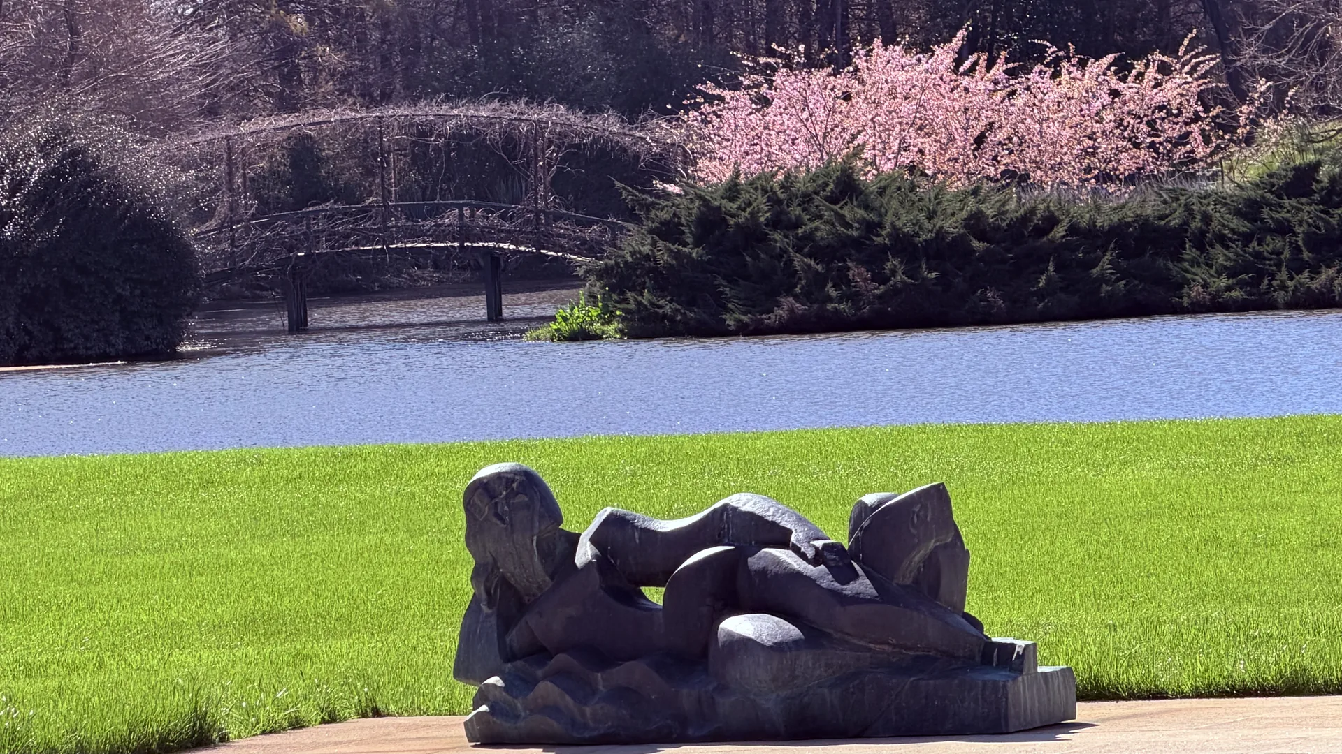 Escultura junto al agua y árboles en flor